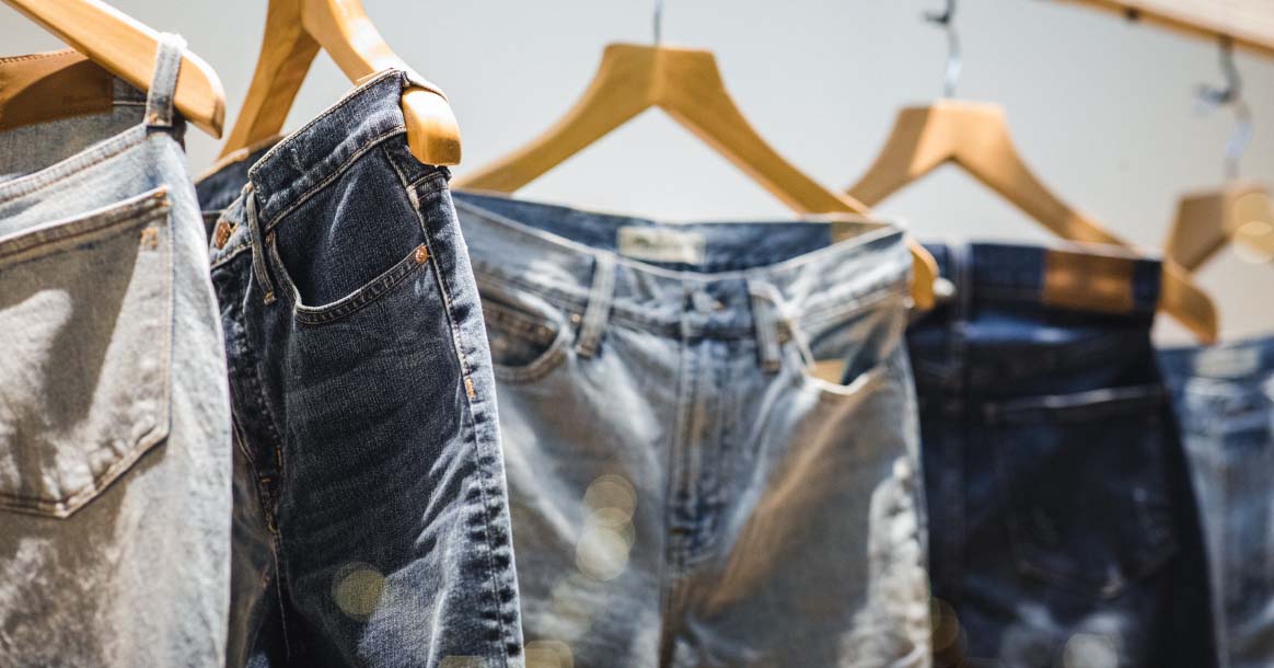 different shades of jeans on wooden hangers