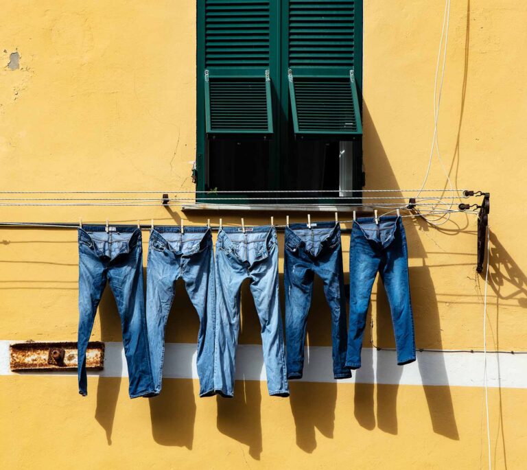 five pairs of blue jeans drying on the sun