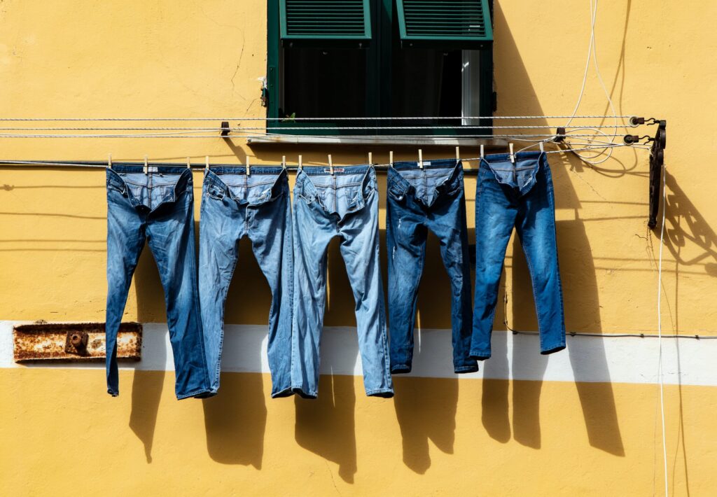 five pairs of blue jeans drying on the sun